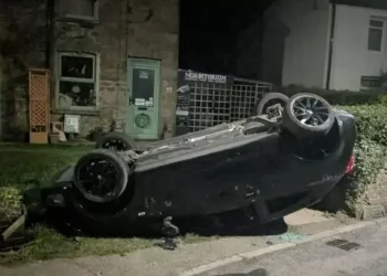 Boy arrested after car found upside-down in garden